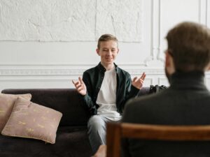 Man in Black Suit Jacket Sitting on Brown Wooden Chair